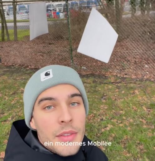 Ein Mann mit Mütze und Hut schaut in die Kamera.