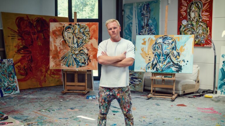 Das Bild zeigt Leon Löwentraut vor seinen Kunstwerken.