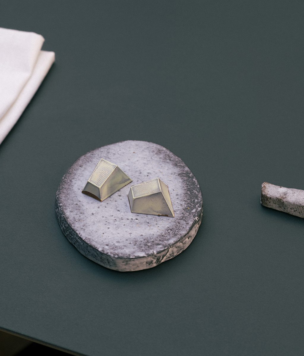 Zwei Pralinen liegen auf einem kleinen runden Teller aus Beton